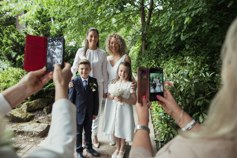 Two brides pose for wedding photos with their kids during a blended family wedding ceremony