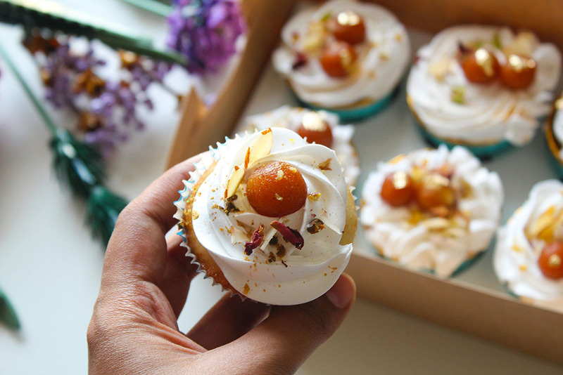 A woman holds out a beautifully decorated Gulab Jamun wedding cupcakes