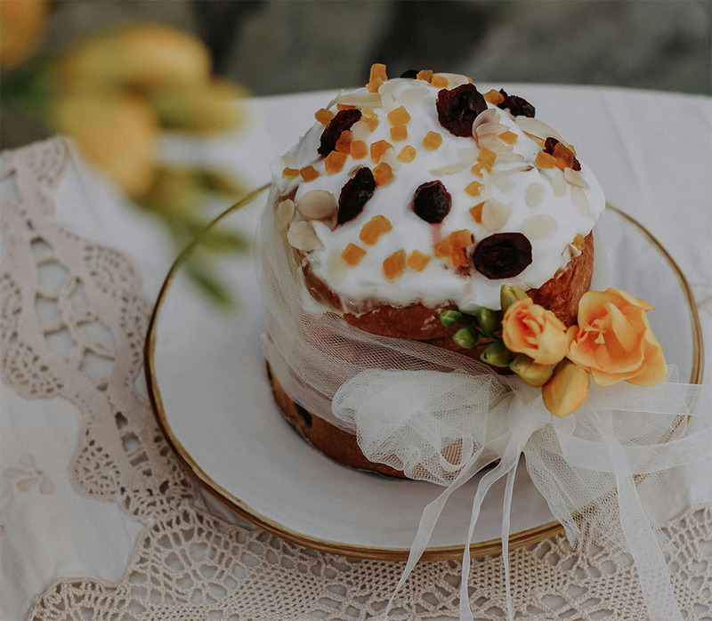 A beautiful fruitcake with white icing and flowers, with a ribbon around it as decoration