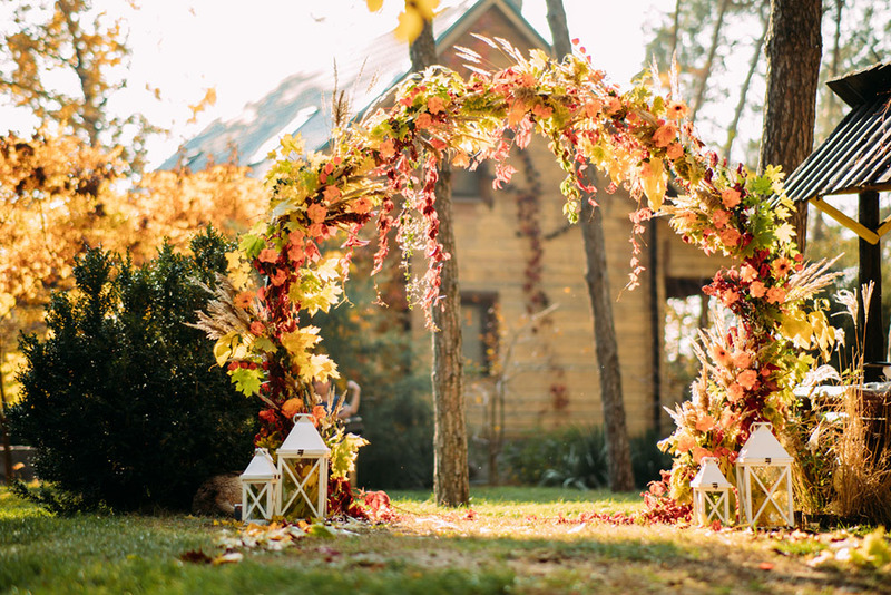 A beautiful wedding arch decorated with fall flowers and leaves