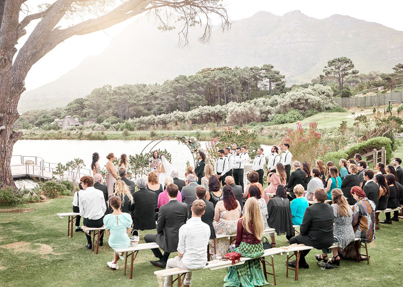 A beautiful outdoor wedding with many friends and family members, mountains in the background. 