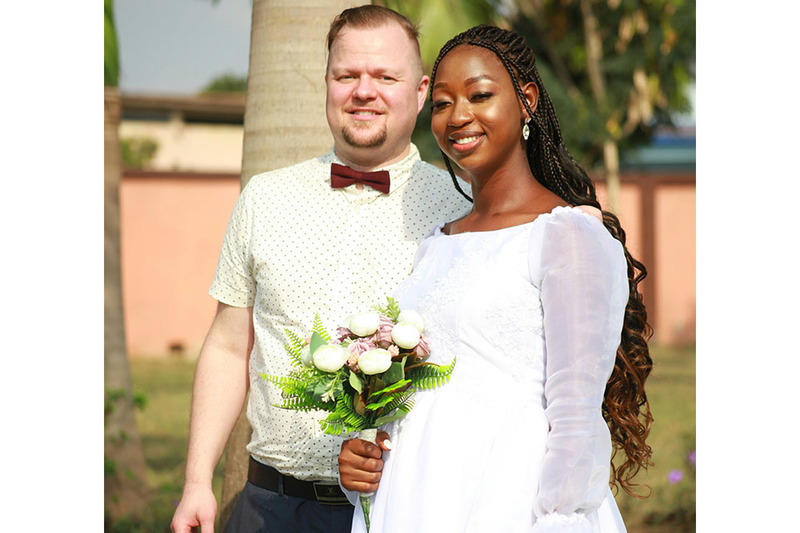 Groom and bride pose in the sunshine, smiling