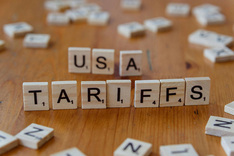Scrabble game tiles on a table spelling out 'USA' and 'TARIFFS'