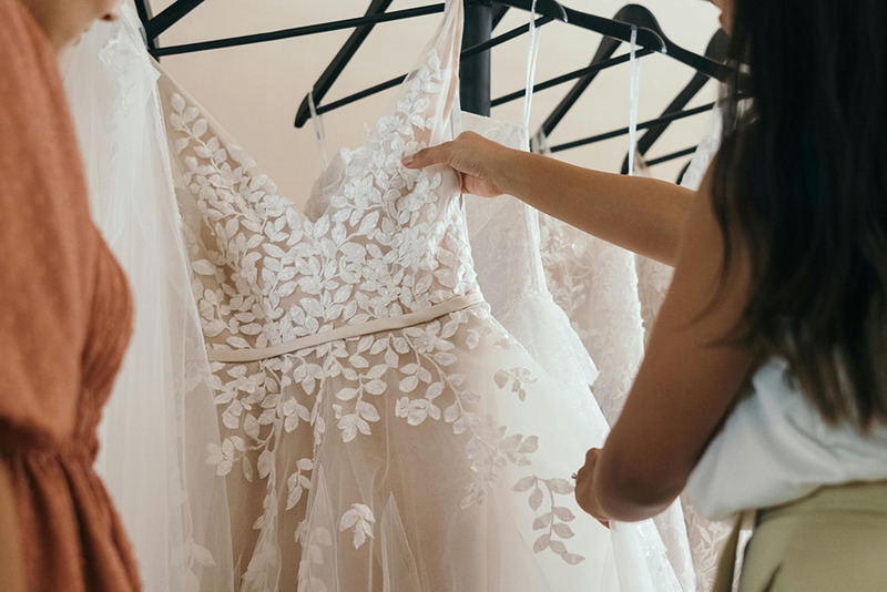 Woman shops for a wedding dress, admires a white dress with lace top