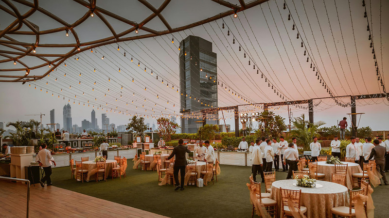 Beautiful city patio decorated for wedding reception with tables, lights, flowers, and staff