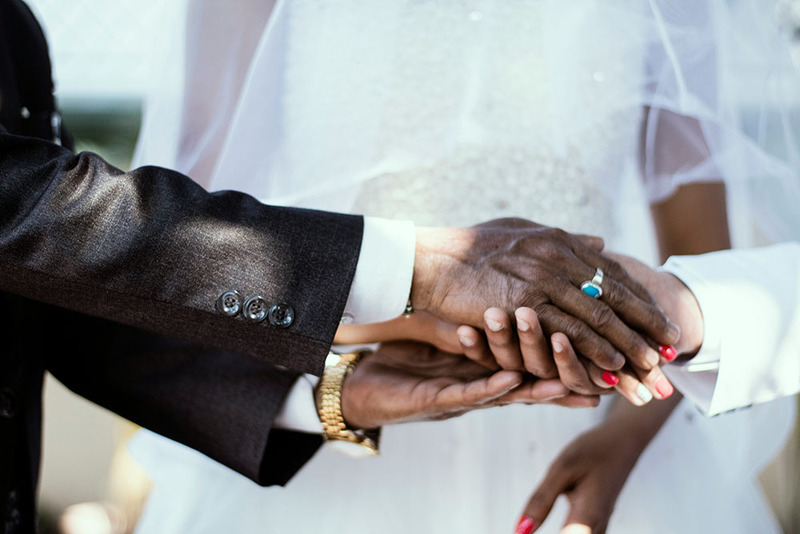 A father holds a groom's hand in blessing after walking bride down the aisle