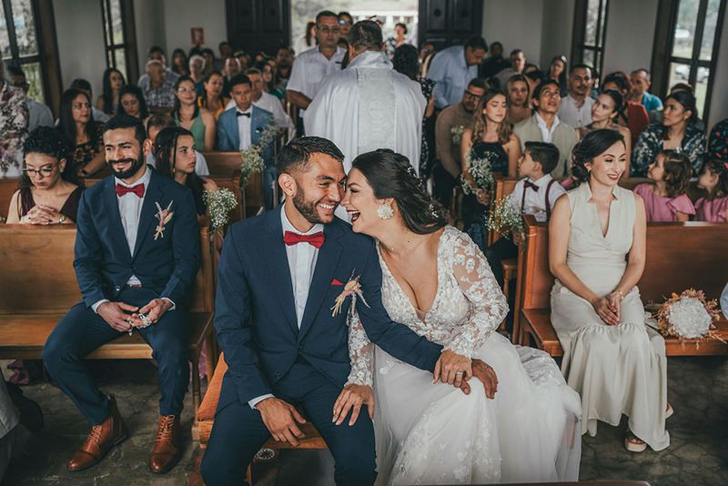 bride and groom sit together at the front of the room, behind them, guests fill the pews