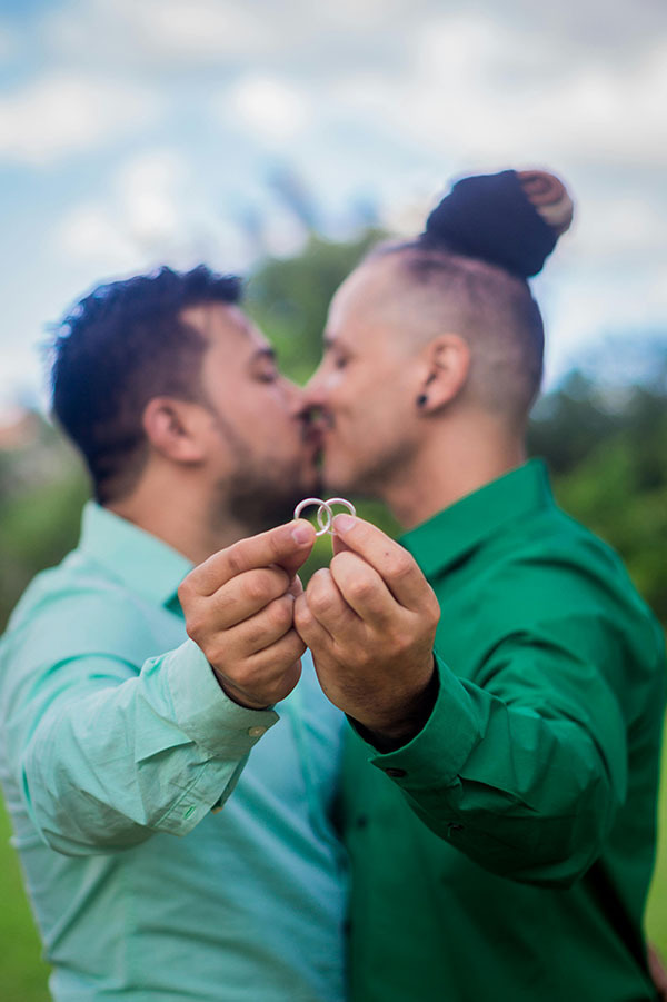 Two men kiss and hold out their wedding rings 
