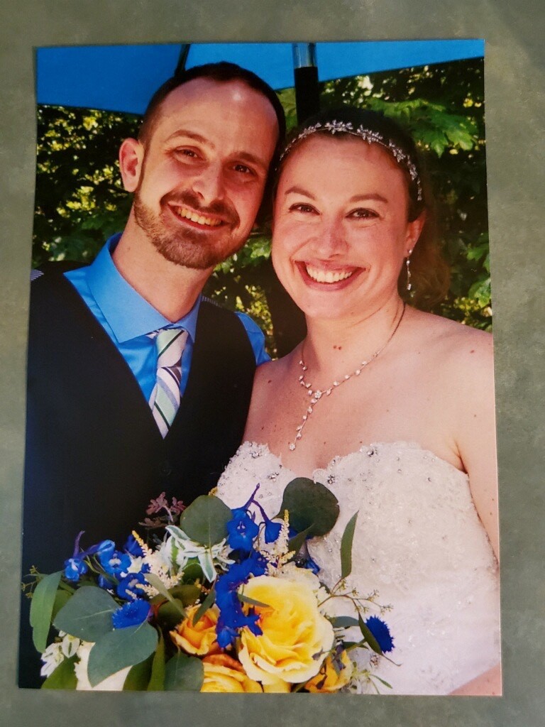 Stephanie and Brian smile on their wedding day, posing for a photo in their beautiful wedding attire