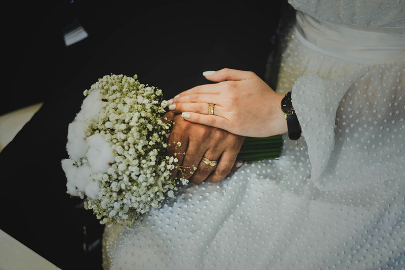 Close up photo of a bride and groom's hands, showing their rings