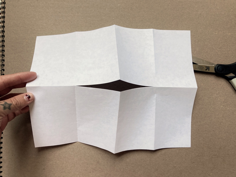 how to fold a zine, the paper has a small cut in the center, where it will be folded