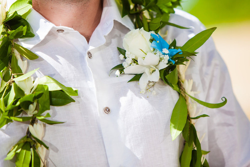 Groom in white button up shirt, tropical boutonniere, and wedding garland lei