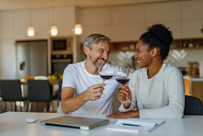 Engaged couple toast glasses of wine at home after signing their prenuptial agreement