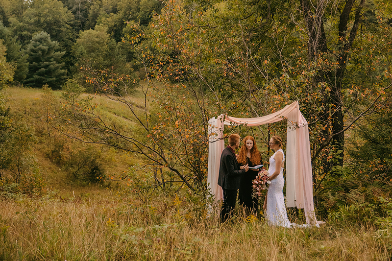 Couple eloping outdoors with wedding officiant in a beautiful forest setting