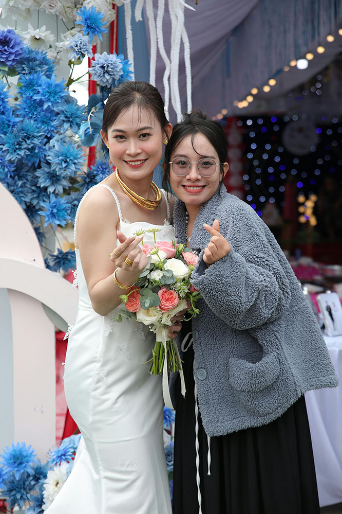 Bride stands with a friend at the wedding, making heart shapes with their hands