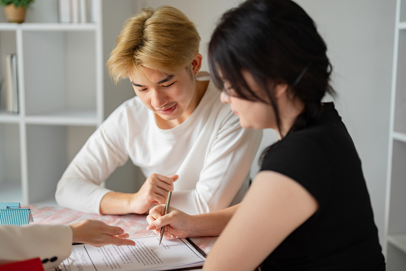 a young couple looks over financial documents with a legal expert