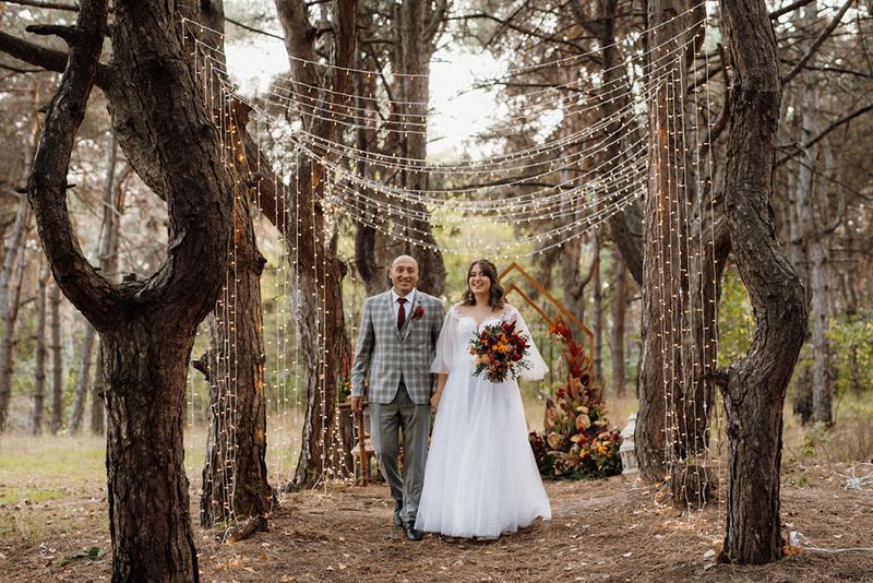 Fall wedding scene, bride and groom and autumn wedding decor in the woods
