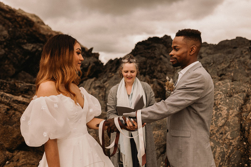 A bride and groom pose with their friend officiant on the wedding day in the desert