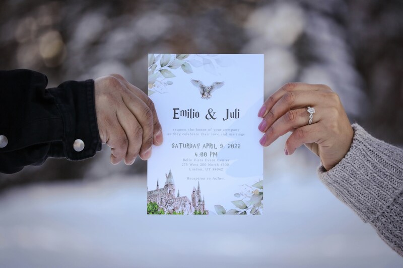 close up of engaged couple holding their wedding invitation together outdoors