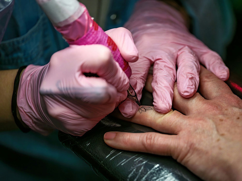 Close up as tattoo artist creates a ring finger tattoo