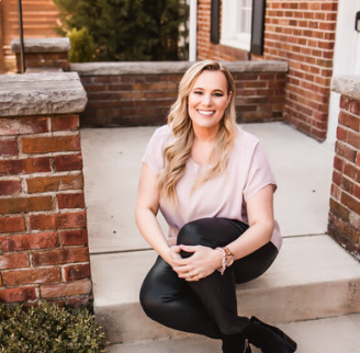 Wedding planner Lisa VanHorton sits outside on steps, smiling at the camera in a stylish business casual outfit