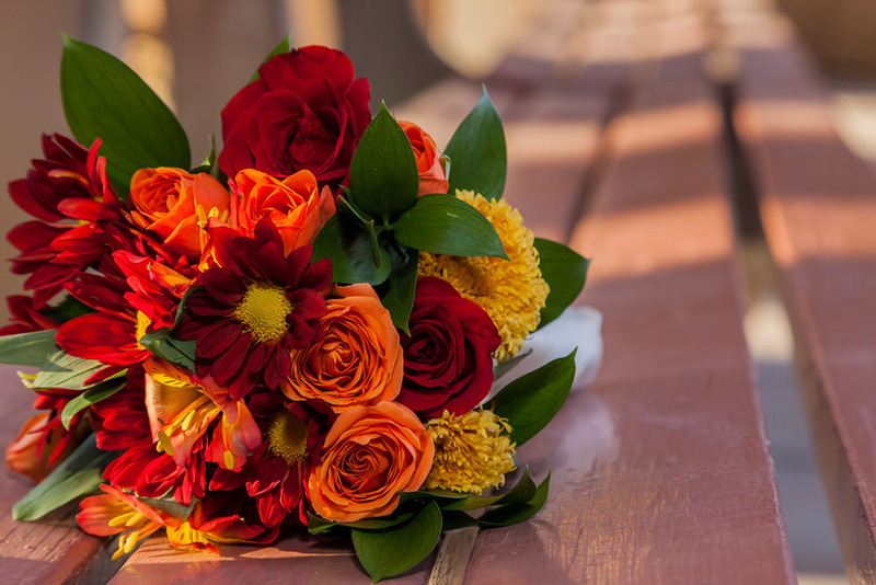 Close up of vibrantly colored red and orange fall wedding flowers