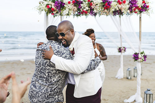 El oficiante de la boda abraza a su amigo, el novio, al final de la boda en la playa.