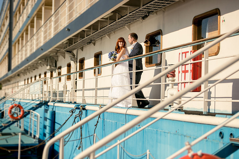 Los novios posan con sus trajes de boda en la cubierta de un crucero.