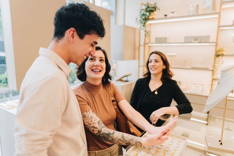 Engaged couple shops for engagement rings together, happy and smiling