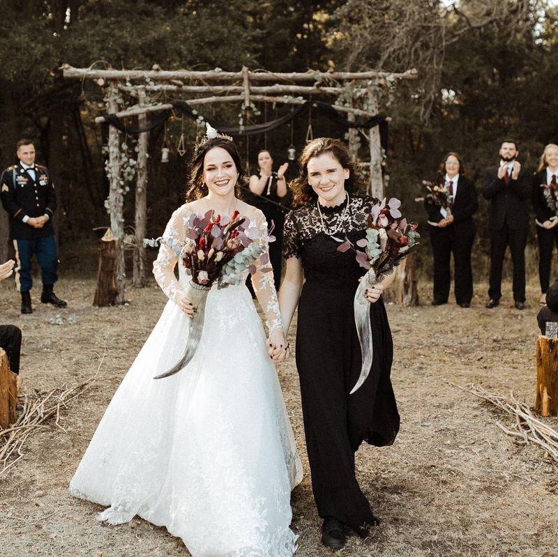 Two brides walk down the aisle holding hands on the wedding day