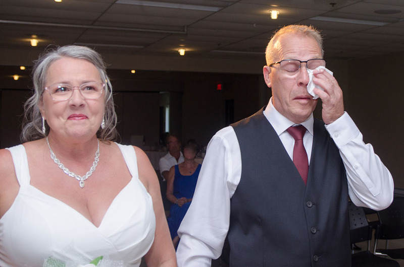 Novios de edad avanzada el día de su boda. La novia sonríe y el novio se seca las lágrimas de felicidad con un pañuelo.