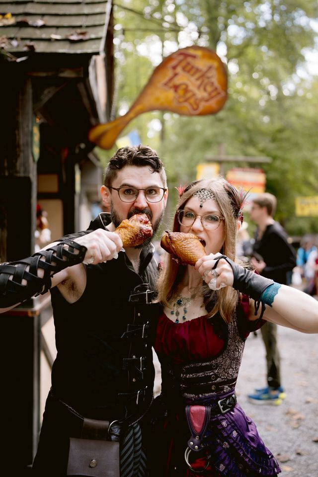 Newlyweds pose with giant turkey legs outdoors after their ren faire wedding ceremony