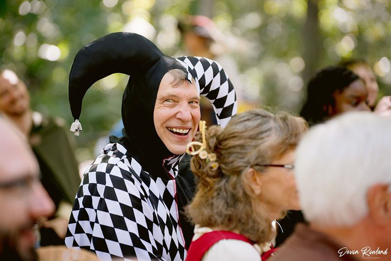 Smiling guest in jester costume at ren faire wedding