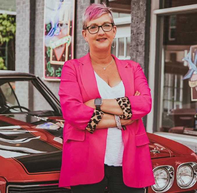 wedding officiant margaret hall poses in a pink jacket
