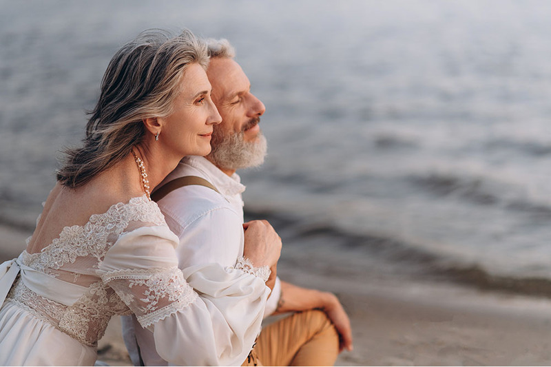 Older couple posing together on beach for vow renewal photos