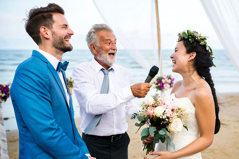 Friend officiant poses with bride and groom during wedding ceremony