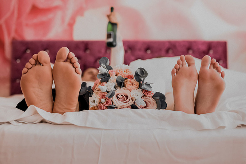 bride and groom laying down in bed barefoot
