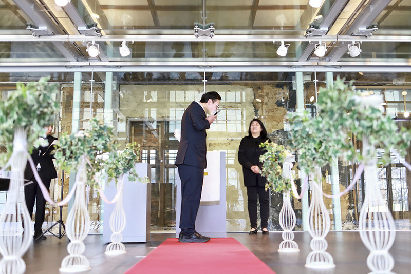 A young groom kisses the screen of his tablet, holding his fictional beloved, during a symbolic ceremony