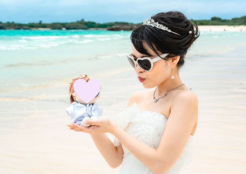 woman in wedding dress poses with plush doll on beach