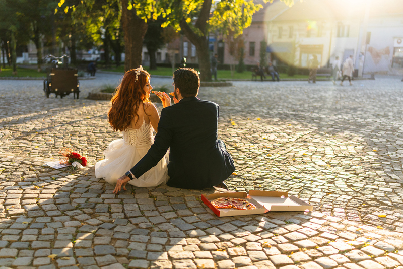 bride and groom eating pizza alone in the sun