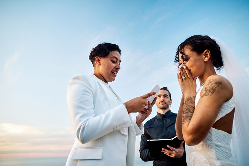 wedding officiant stands to the side as brides exchange vows
