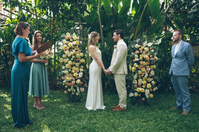 Tropical elopement ceremony, officiant reads while bride and groom hold hands