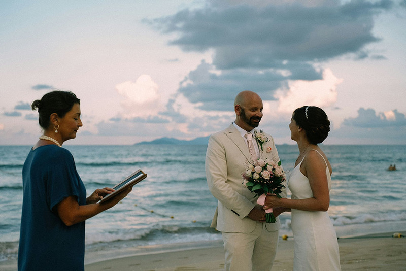 Wedding officiant performs ceremony on the beach with bride and groom
