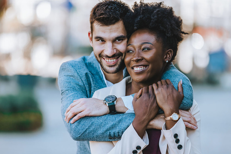 Friends hugging and smiling outdoors