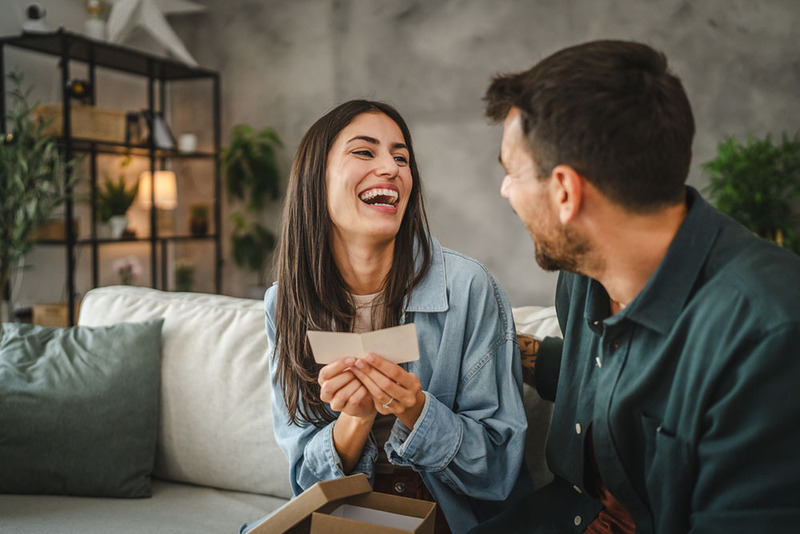 Newlyweds reading love notes and laughing at home on couch