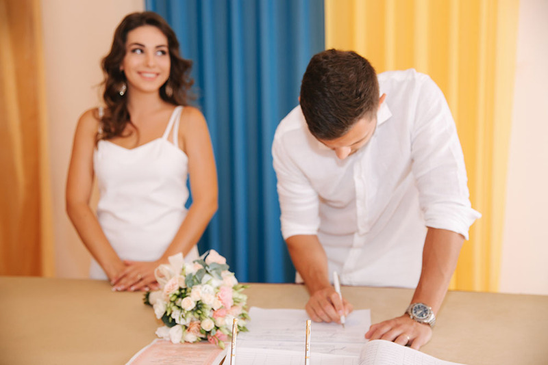 Groom signing a marriage agreement while bride smiles