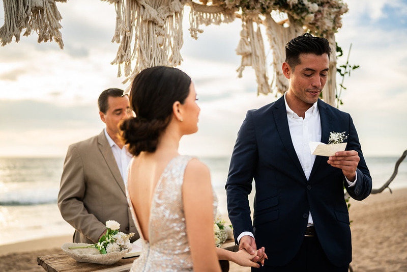 Groom reads his marriage vows to bride during beach wedding ceremony