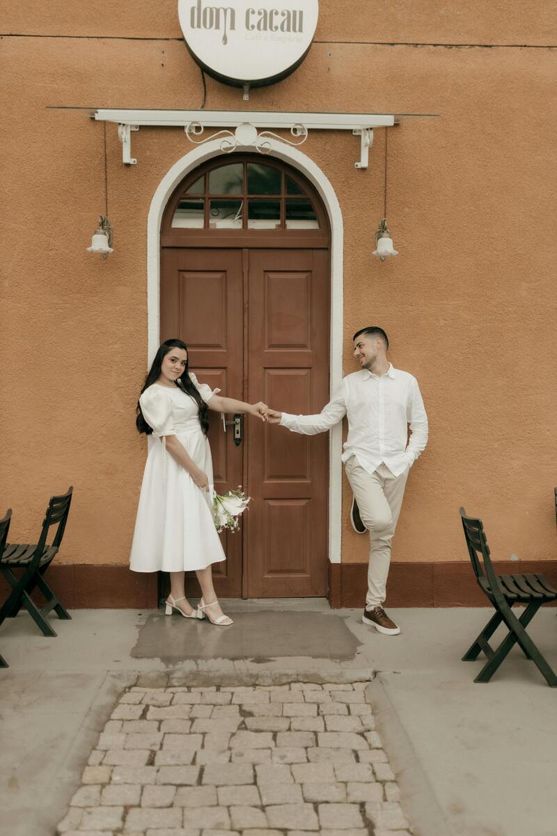 young couple pose in front of cafe on wedding day