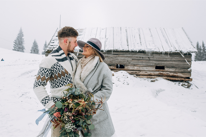 newlyweds bride and groom pose in snow