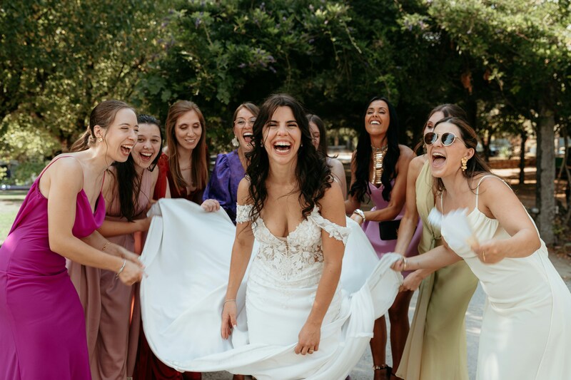 bride with bridesmaids laughing posing